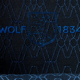Close-up of dark apple leather fabric with an embroidered crest featuring a wolf, geometric designs, and the text "WOLF 1834" in blue stitching—an elegant detail found on the WOLF Earth Triple Watch Roll, a premium watch storage accessory.