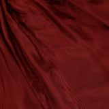 The ZIMMERMANN Aster Gathered Bead Blouse features deep burgundy sheer fabric gathered with gold rings, creating soft pleats and a subtle shine for an elegant, merlot-inspired look.