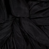 Close-up of the black, shiny, pleated fabric from ZIMMERMANN'S Aster Scarf Silk Midi Dress, featuring overlapping layers and folds for a textured and slightly glossy look.