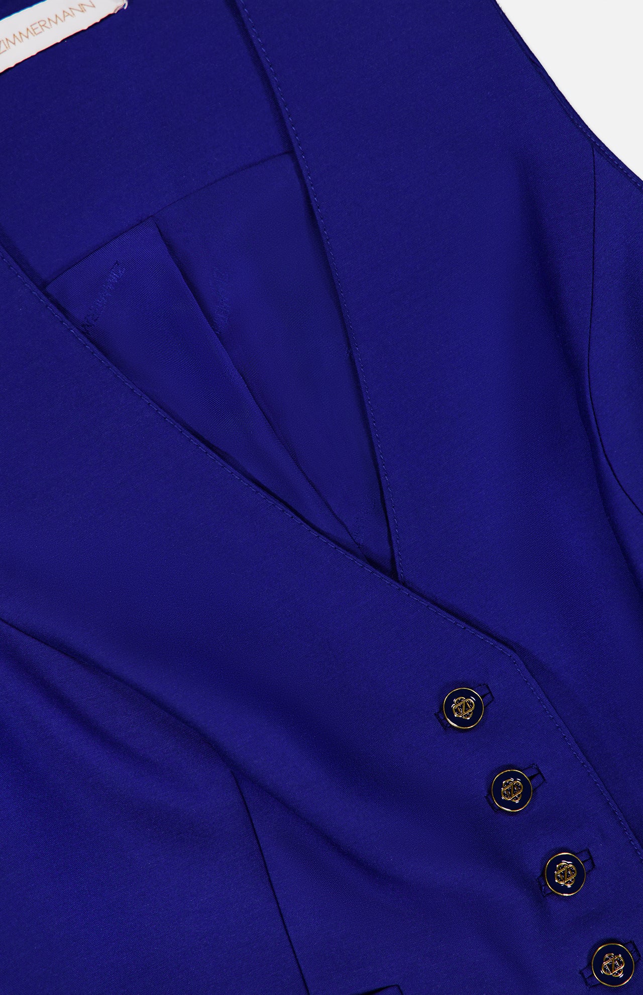 Close-up of a cobalt blue Zimmermann Clash Wool Silk Waistcoat in a cropped silhouette, featuring a V-neckline and four gold-toned buttons with embossed detailing.
