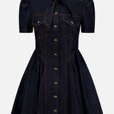 Introducing the ZIMMERMANN Denim Corset Mini Dress: a short-sleeve dark denim mini dress featuring a flared skirt, puffed shoulders, and distinctive gold buttons down the front. Designed with two chest pockets and a tied neck bow, this dress stands out with orange stitching accents along the seams and details. Subtle corset-style shaping offers a flattering silhouette.