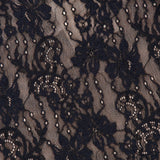 Close-up of the ZIMMERMANN Stretch Lace Bodysuit in black, showcasing an intricate floral pattern over a light beige mesh lining. The delicate stretch lace fabric features flowers and leaves accented by fine mesh and small dot details, highlighting the elegant beauty of this bodysuit.