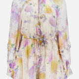 The Luna Ruffle Floral Playsuit by ZIMMERMANN features long sleeves, a high neckline, cinched waist, and ruffled trim. Sheer fabric showcases pastel purple, yellow, and pink florals on a light base for an effortlessly chic style.