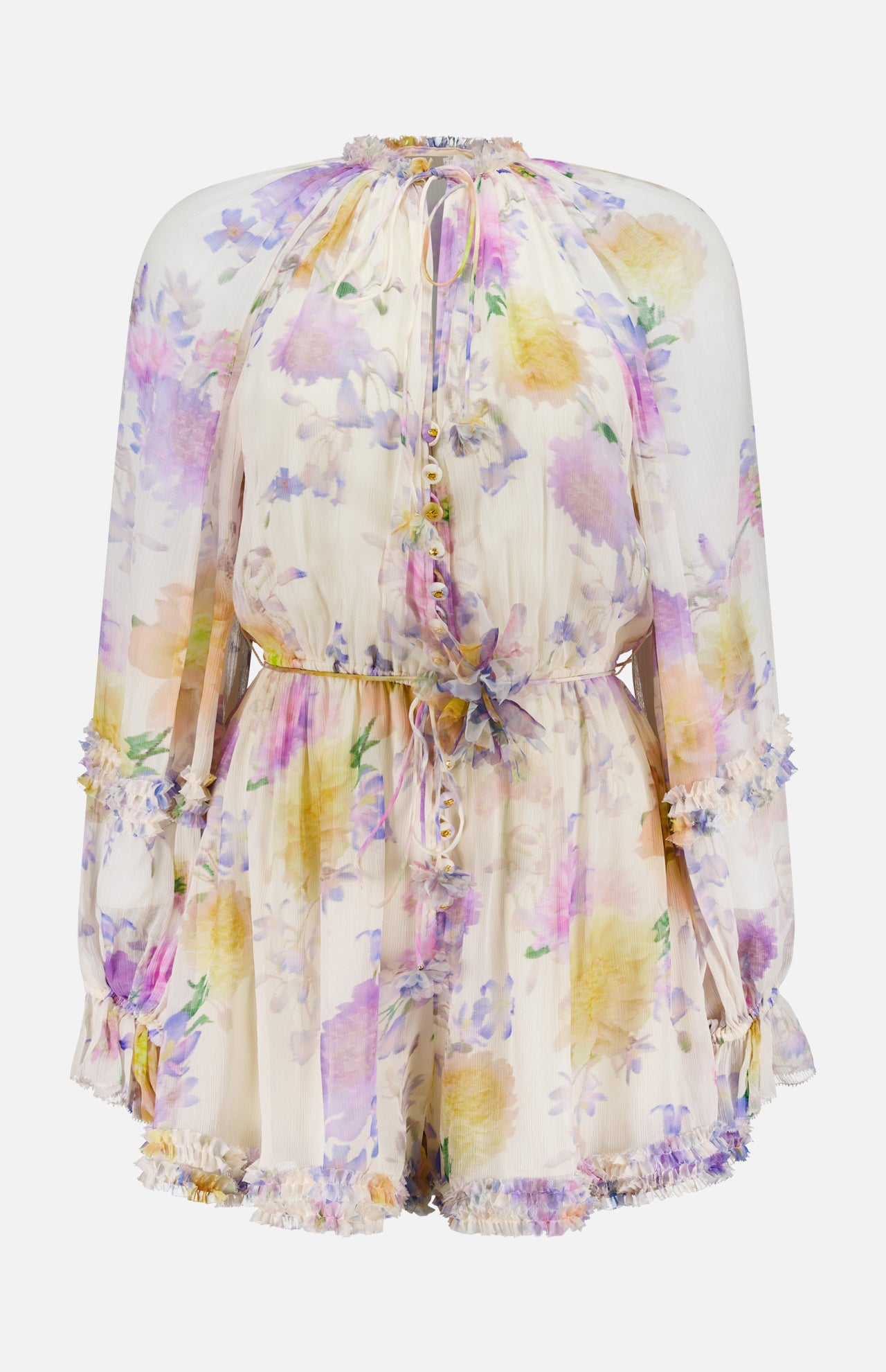 The Luna Ruffle Floral Playsuit by ZIMMERMANN features long sleeves, a high neckline, cinched waist, and ruffled trim. Sheer fabric showcases pastel purple, yellow, and pink florals on a light base for an effortlessly chic style.