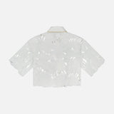 The Mahon Embroidered Crop Shirt by ZIMMERMANN is a sheer ivory cotton blouse with short sleeves, leaf-pattern embroidery, a pointed collar, gold chain detail at the neckline, and a relaxed cropped fit. Displayed on a plain white background.