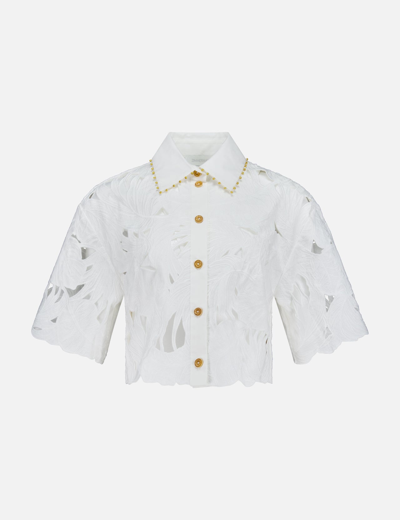 The ZIMMERMANN Mahon Embroidered Crop Shirt is an ivory short-sleeve button-up blouse with a floral cut-out pattern, gold buttons, scalloped edges, and embroidered cotton detail along the collar.