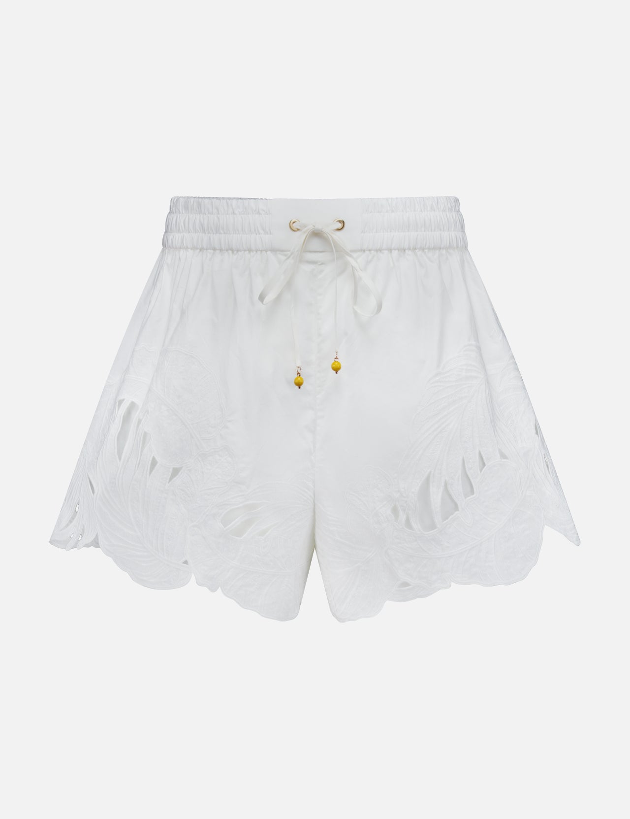 The ZIMMERMANN Mahon Embroidered Drawstring Short features an ivory hue, gold bead accents, and leaf-patterned cutouts along the scalloped hem. Made from cotton, these high-rise shorts are shown against a plain white background.