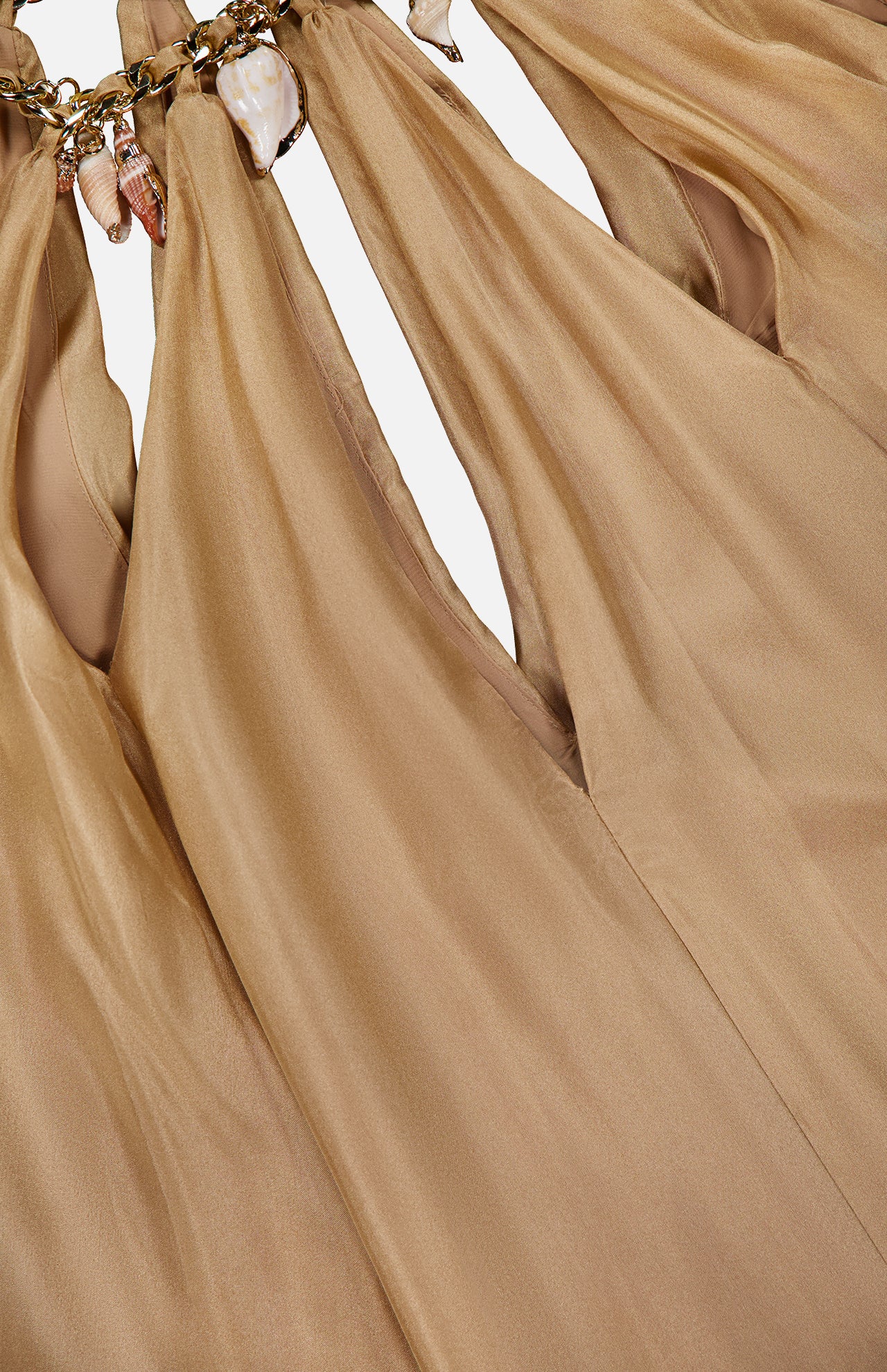 Close-up of light brown, silky fabric from the ZIMMERMANN Mahon Shell Charms Maxi Dress, gathered with gold chain links and delicate seashell charms for luxurious folds and elegant texture.