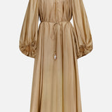 The Mahon Shell Charms Maxi Dress by ZIMMERMANN is a long-sleeved gold silk habutae dress with a cinched waist, gathered neckline, full billowy sleeves, keyhole neck detail, and tasseled waist tie.