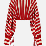 The ZIMMERMANN Rebellion Drawn Cuff Sweater features a cropped fit, long blouson sleeves, red and cream vertical and diagonal stripes, and cinched cuffs and hem with adjustable drawstrings for a bold look.