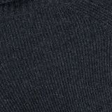 Close-up of the dark gray ribbed knit fabric of the Valiant Buttoned Sweater by ZIMMERMANN, highlighting the texture and pattern of the material.