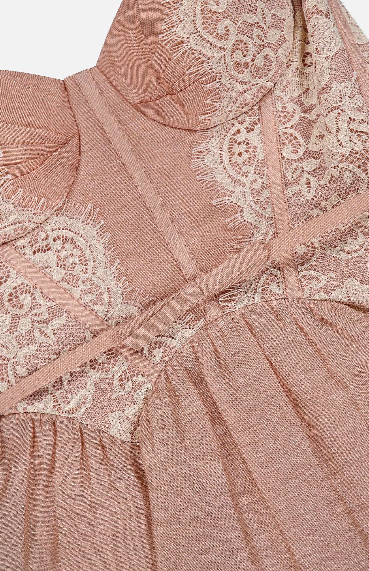 Close-up of the Valiant Lace Trim Mini Dress by ZIMMERMANN, featuring blush pink fabric with cream lace trim and intricate stitching that highlights the delicate texture and elegant design of this romantic piece.