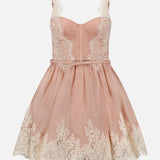 ZIMMERMANN’s Valiant Lace Trim Mini Dress is a blush pink romantic mini dress, featuring a fitted lace bodice with a sweetheart neckline and a flared skirt. Intricate cream lace detailing decorates the hem and bodice, capturing the timeless elegance of ballerinacore style.