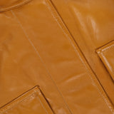 Close-up of a Zimmermann Valiant Leather Biker Jacket in amber, featuring a collar with brass-toned snap buttons and two large flap pockets.