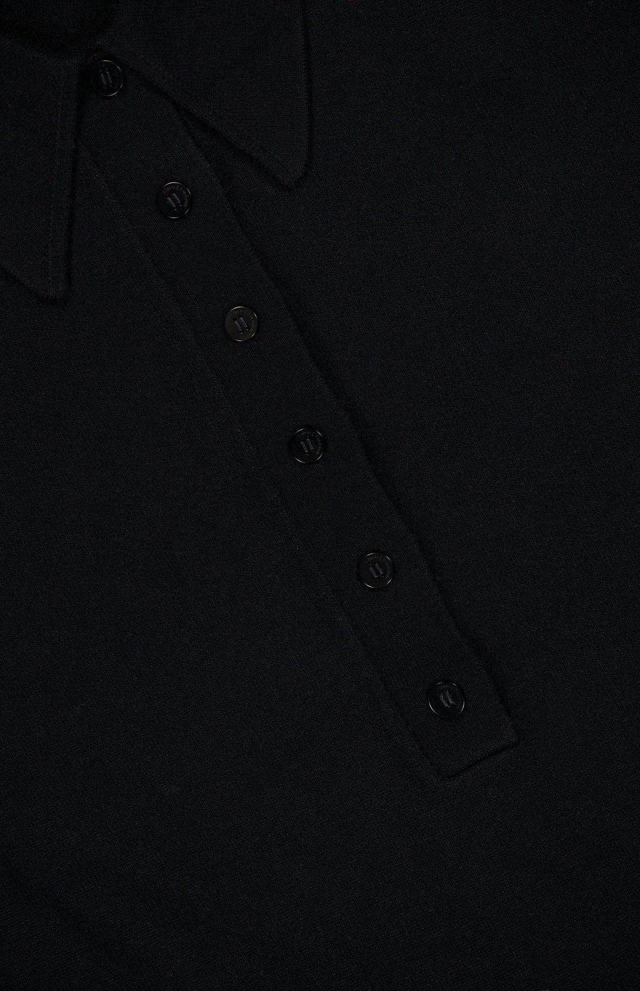 Close-up of the ZIMMERMANN Valiant Merino Lace Dress in black, showcasing its collared neckline and button placket with five matching buttons. The image highlights the refined fabric texture and precise stitch lines, emphasizing the dress’s expert structure and design details characteristic of merino wool craftsmanship.