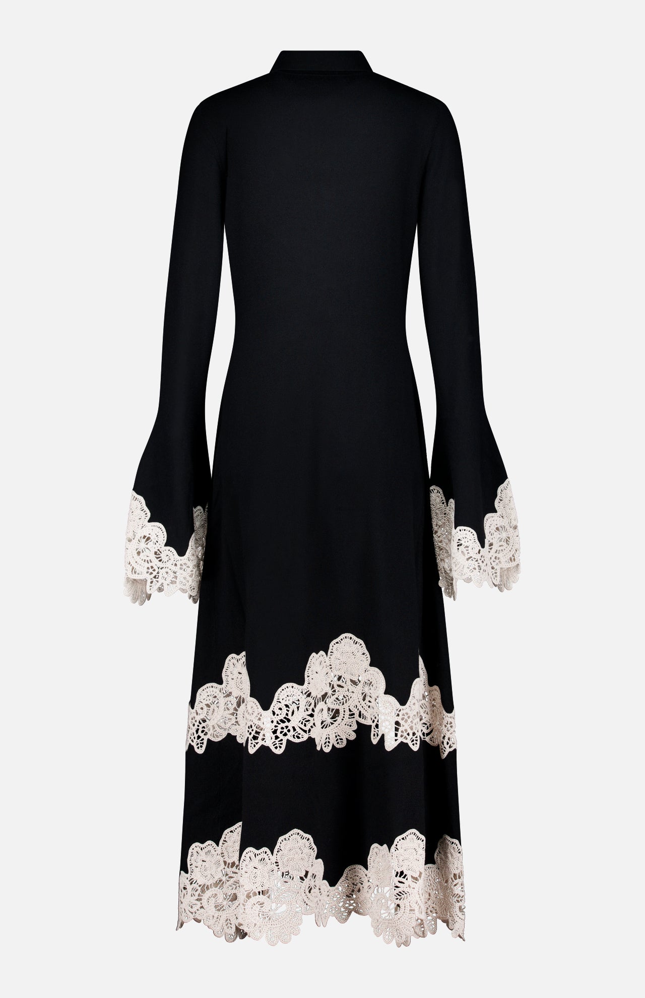 The ZIMMERMANN Valiant Merino Lace Dress is a long black merino wool midi dress with flared sleeves and a gracefully flared skirt, featuring intricate white lace embroidered trim at the cuffs, hem, and near the bottom. It is displayed against a plain white background.