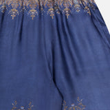 Introducing the ZIMMERMANN Valiant Paisley Print Track Pant—a high-rise, pull-on pant crafted from smooth, slightly glossy fabric for ultimate comfort and elegance. These blue silk pants showcase intricate gold and bronze paisley patterns along the waistband and hem, finished with a detailed ornate border at the top for an elevated touch.