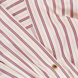 Close-up of the ZIMMERMANN Valiant Tuck Striped Shirt Dress, featuring cream-colored fabric with vertical red and navy blue stripes, gold buttons, and a visible brand label in the top left corner.