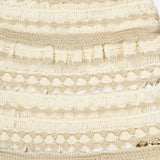 Close-up of the Wanderlust Crochet Midi Skirt by ZIMMERMANN, showcasing cream and gold woven trim with metallic threads, ruffled details, and varied textures in horizontal layers against a white background.