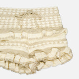 A close-up of the Wanderlust Crochet Short by ZIMMERMANN shows its cream color, hand-knitted texture, and ruffled edges, highlighting delicate craftsmanship against a white background.