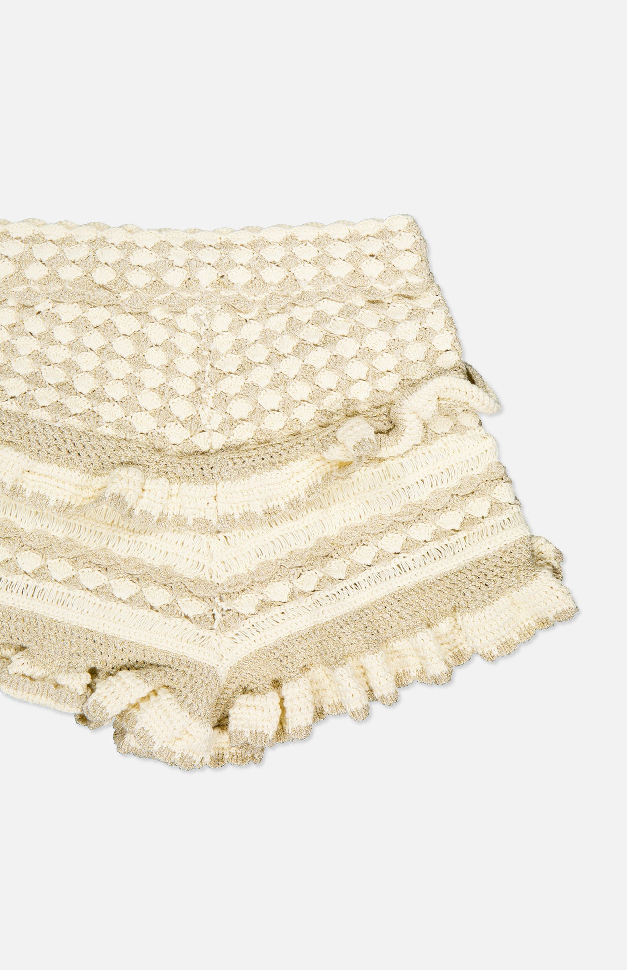 The Wanderlust Crochet Short by ZIMMERMANN features a beige, textured design with scalloped hems, decorative patterns, and layered ruffles along the legs and waistband.