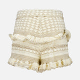 The ZIMMERMANN Wanderlust Crochet Short features a cream color, high-waisted fit, textured patterns, ruffled edges, and decorative pom-poms, shown against a plain white background.