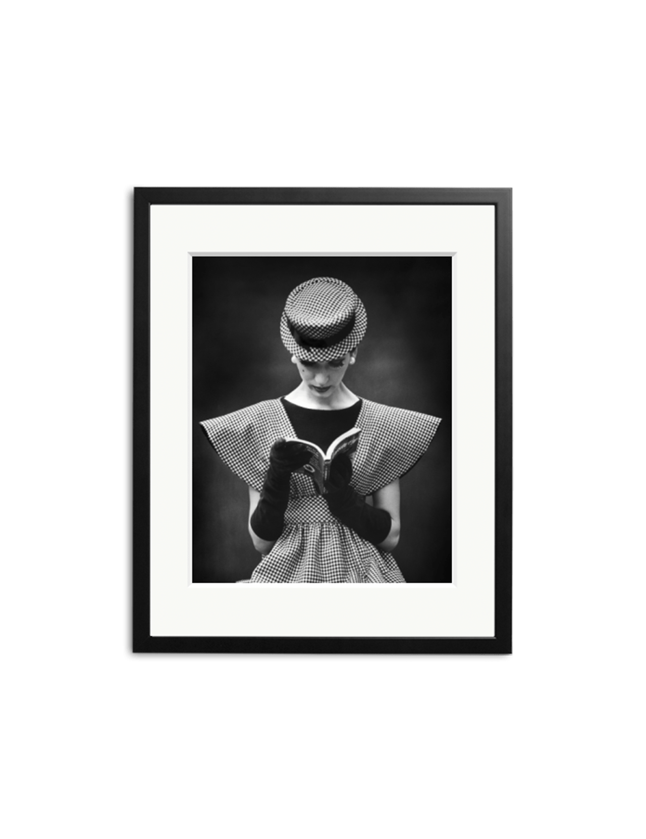 The Wide Shoulder Look" by SONIC EDITIONS is a black-and-white photo featuring a person in a patterned dress, gloves, and hat reading an open book. Framed in black, this iconic piece makes a striking statement for any home decor.